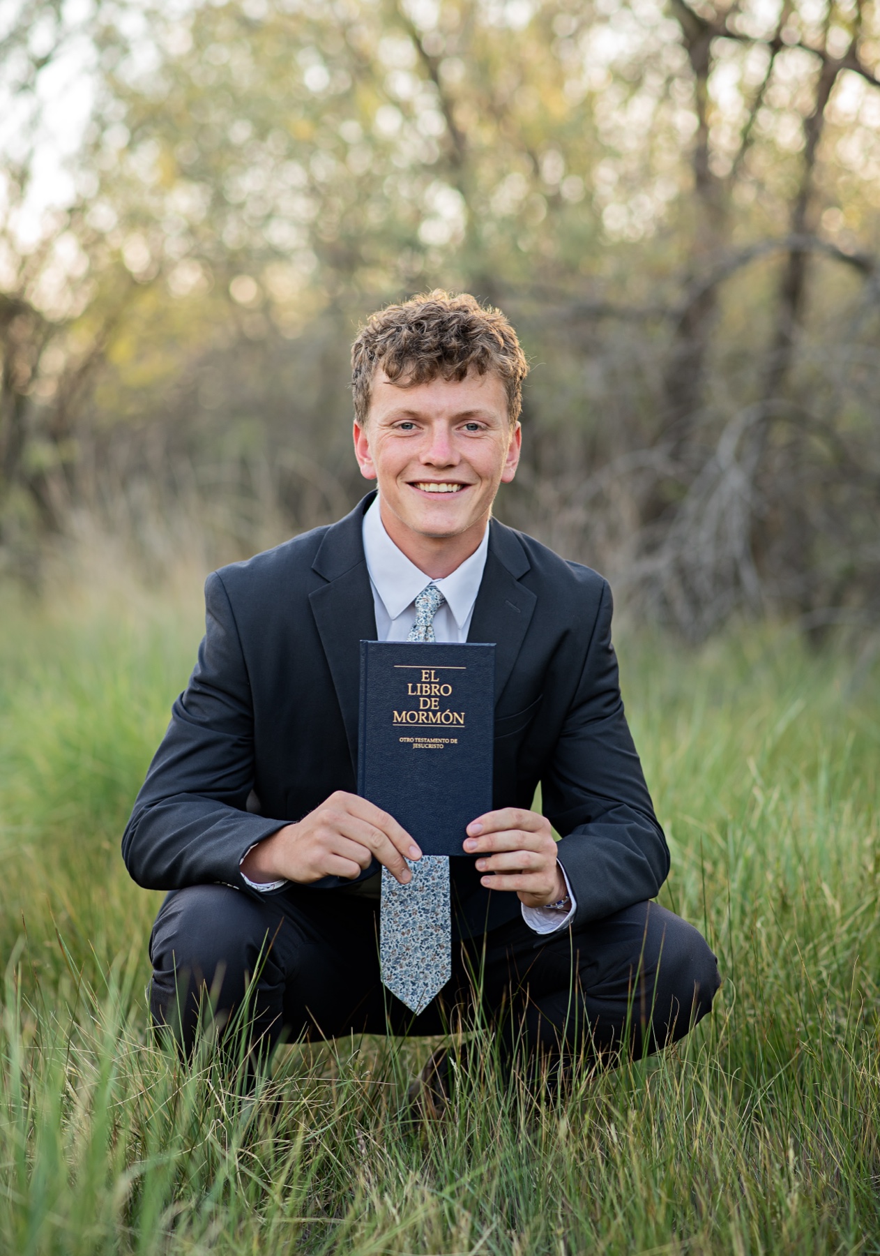 Elder Jared Laws smiling and holding a Spanish Book of Mormon